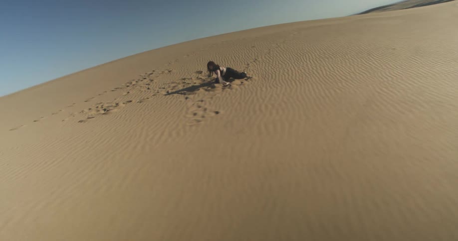 A woman is dancing in the sand of the desert