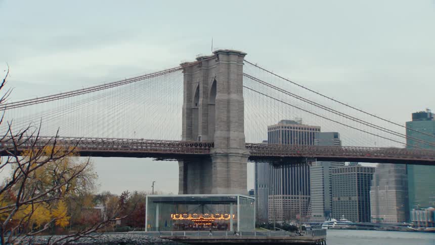 The iconic brooklyn bridge stretches across the east river with its majestic towers and suspension cables against a cloudy sky