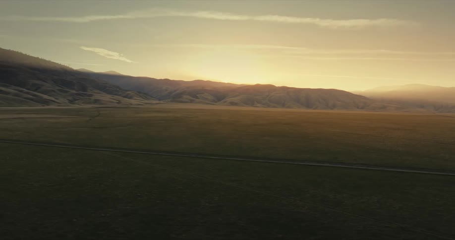Aerial landscape of a vast green field surrounded by mountains