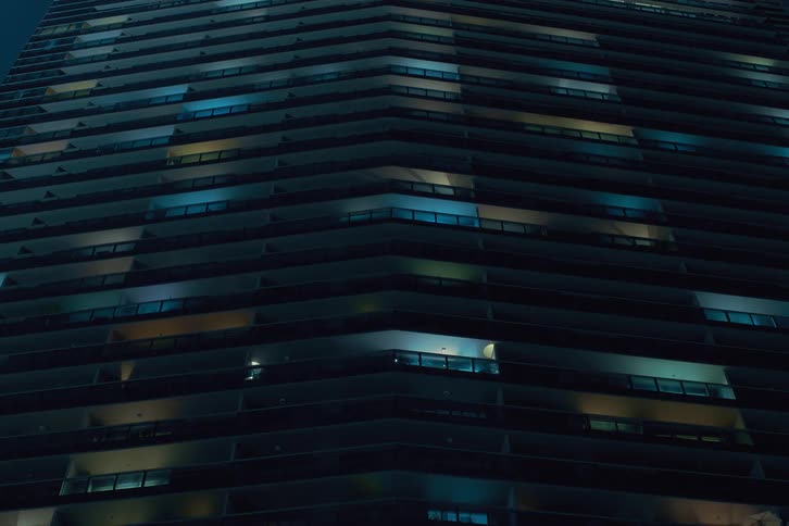 Lights of an urban apartment building flickering at night before turning off