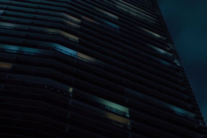 Skyscraper apartment lights turn off as the night passes