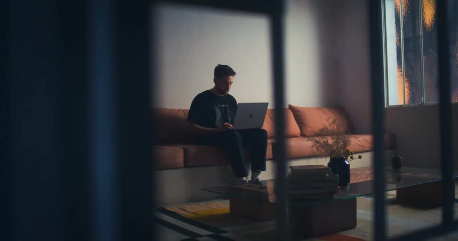 A man is using his laptop on the couch