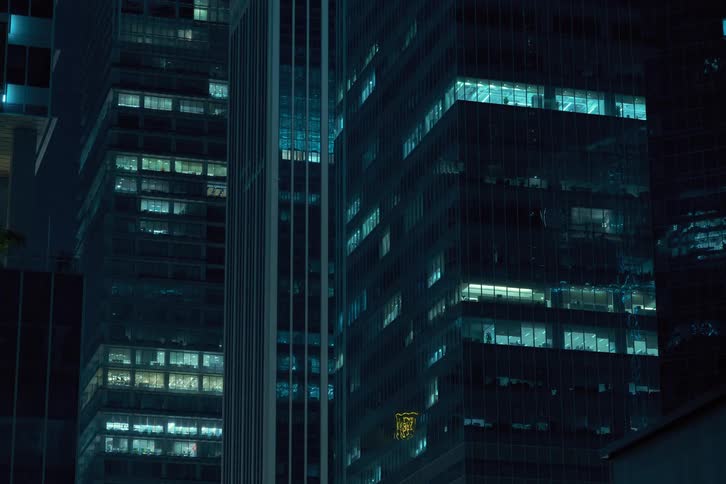 The facade of a modern highrise building at night with the windows turning off in a flickering pattern creating a dynamic grid like effect on the facade