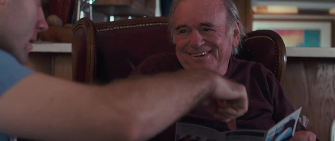 Elderly patient laughs while listening to his home health provider discuss a booklet