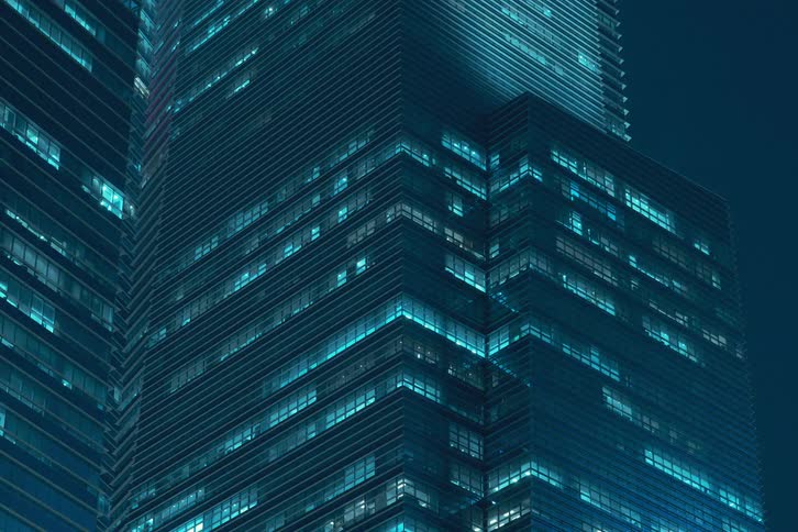 Nighttime view of a modern office building with numerous illuminated windows flickering