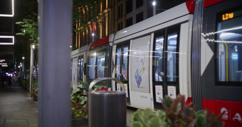 A long trolley travels through the city at night