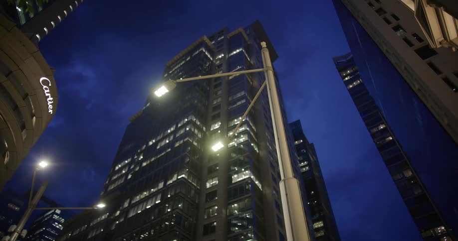 A nighttime cityscape with tall illuminated buildings and streetlights