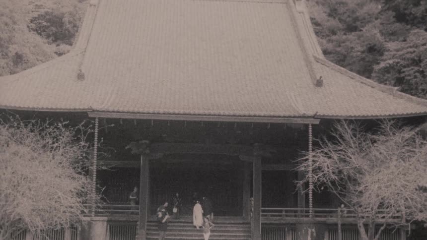 A traditional japanese temple with a curved roof and a large entranceway surrounded by trees