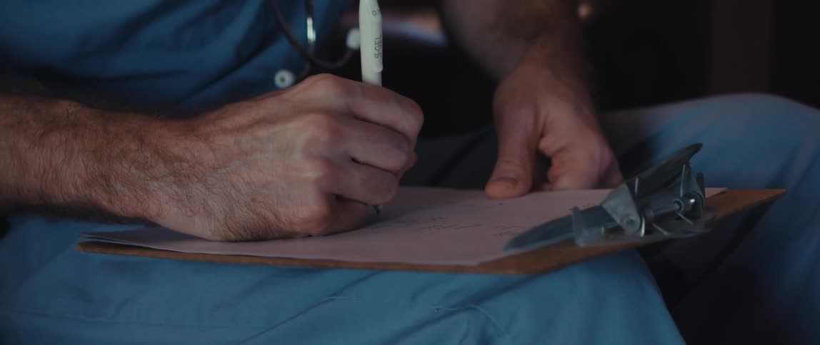 Nurse sitting and taking notes on a clipboard