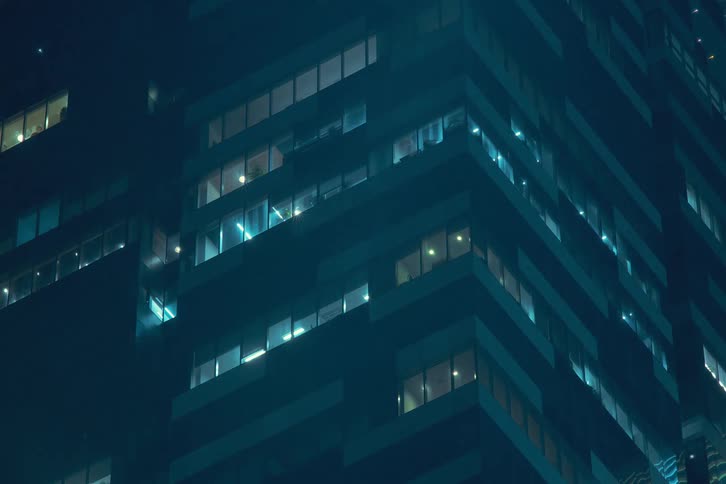 Upward view of a modern building with lights turning off at night