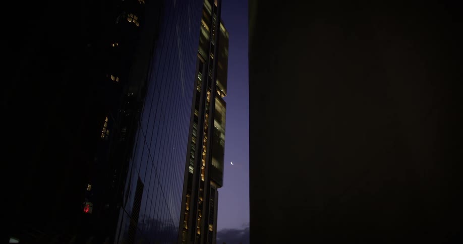 Tall modern skyscrapers with illuminated windows at dusk