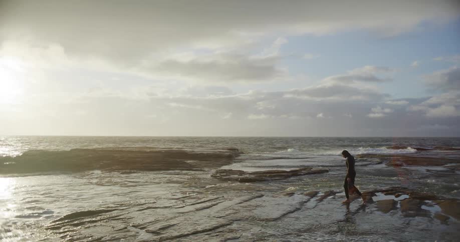 A man is walking on the beach as waves crash on the shore