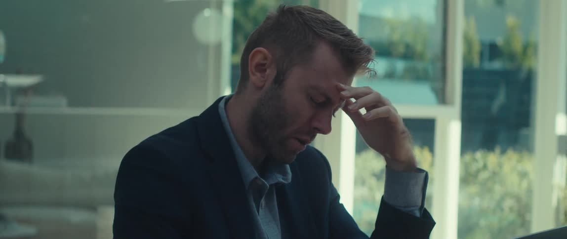 Blond man in blazer sitting talking on cell phone