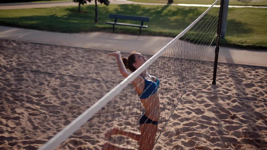 Woman jumping on a sand volleyball court