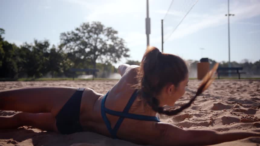 A beach volleyball player dives to make a play on the ball