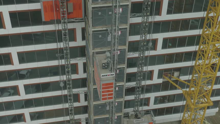 Giant elevators move large containers up and down the side of a building