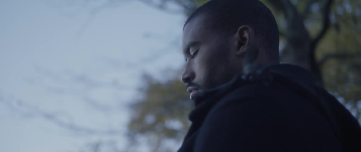 A man stands outside with his eyes closed