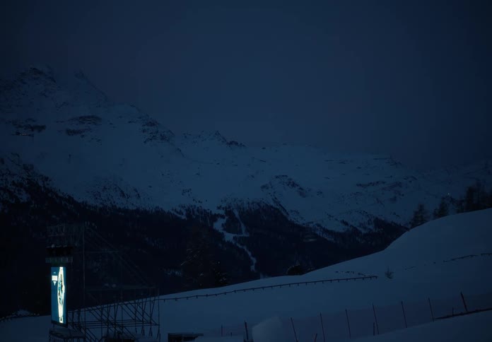 Ski lift passes over a snow covered field near the mountains on a winter night
