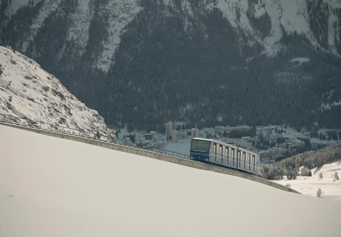 Train descending a snowy mountain with a city in the background