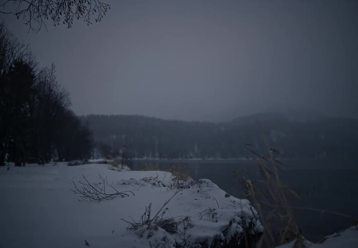 A snowcovered landscape with a lake winding through it creating a serene and wintry atmosphere