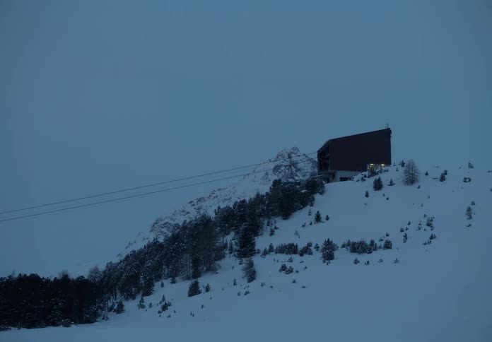 Cable car ascending a snowy mountain in the early evening