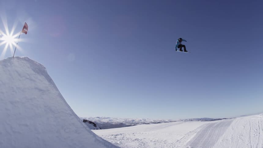 A snowboarder jumps from a snow ramp