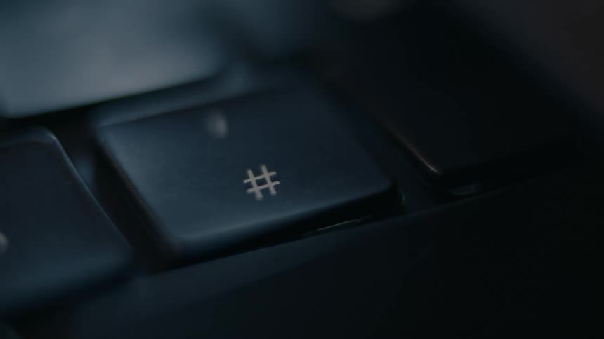 A finger pressing the hashtag key on a keyboard