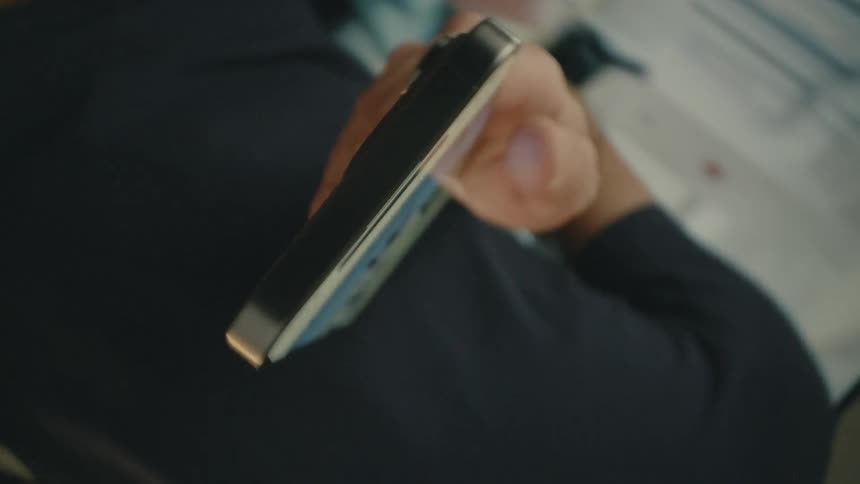 A man scrolls on a smartphone in a room