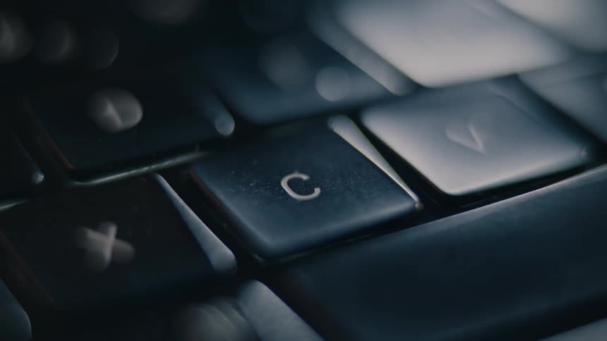 A finger quickly presses a letter on a keyboard