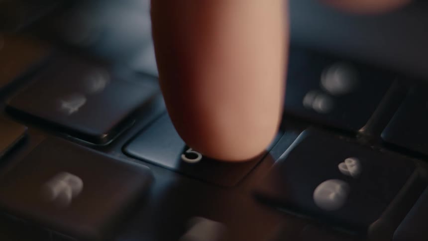 A finger presses the number 5 key on a laptop keyboard
