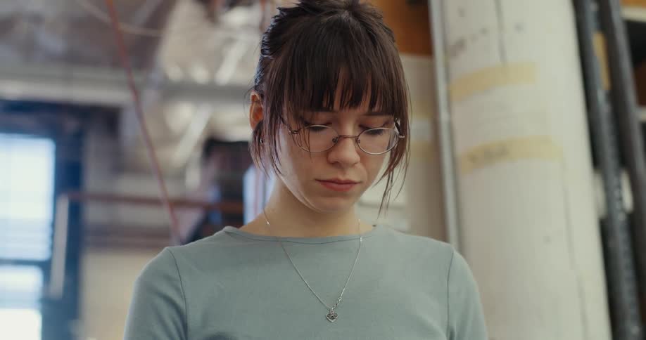 Woman wearing glasses indoors looking down concentrated