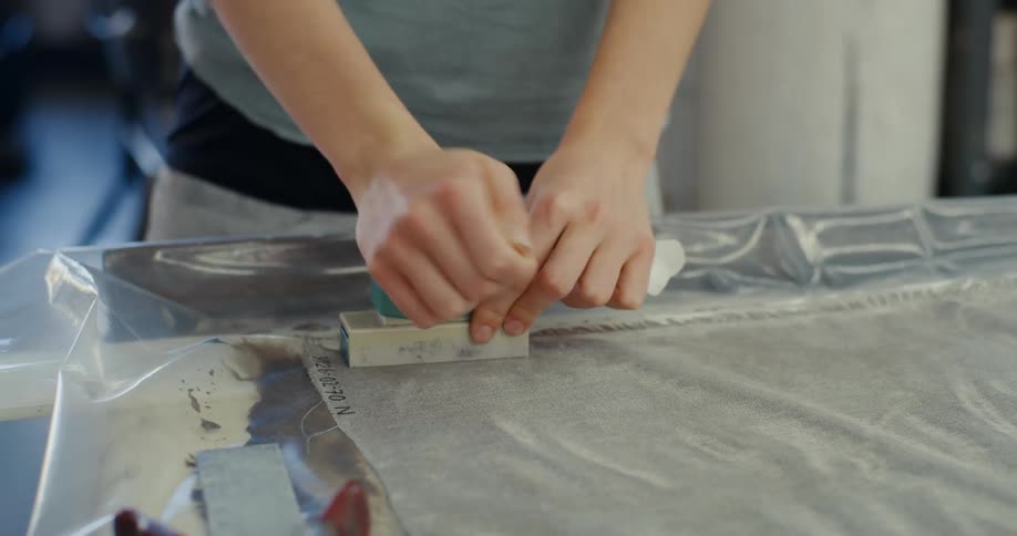 A woman carefully sanding a surface with a block of sandpaper