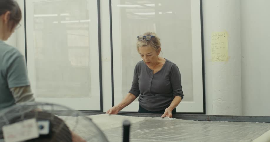 Two women standing working and interacting with a plastic on a surface