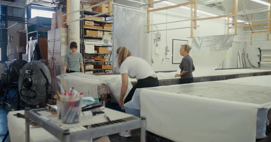 Three women working indoors placing plastic on a surface