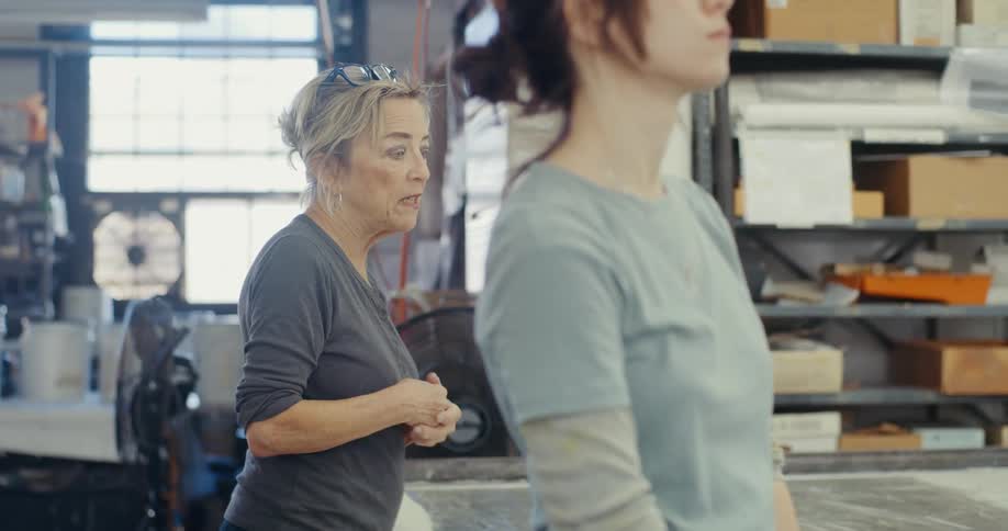 Two women standing and talking to each other while working in an indoor space