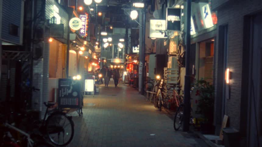 Alley with pedestrians walking at night and lights from commercial establishments
