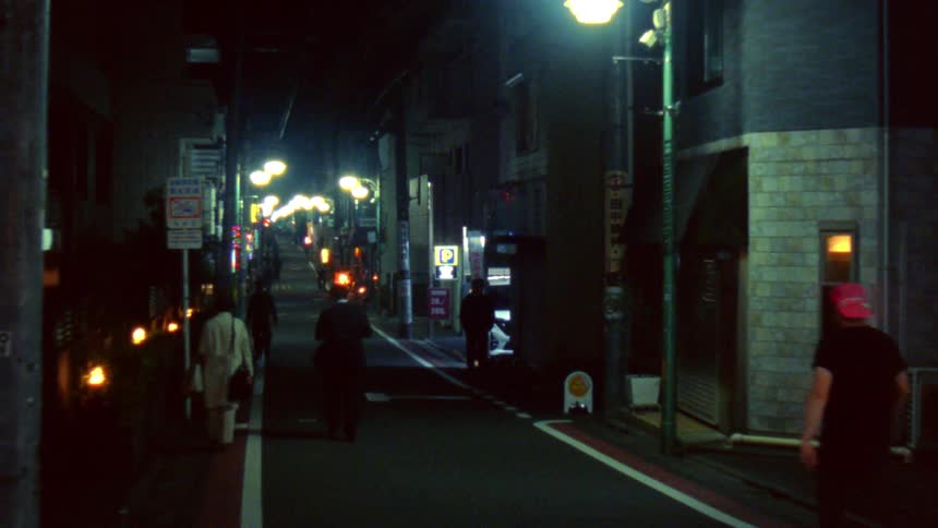 Pedestrians walking along a city street at night