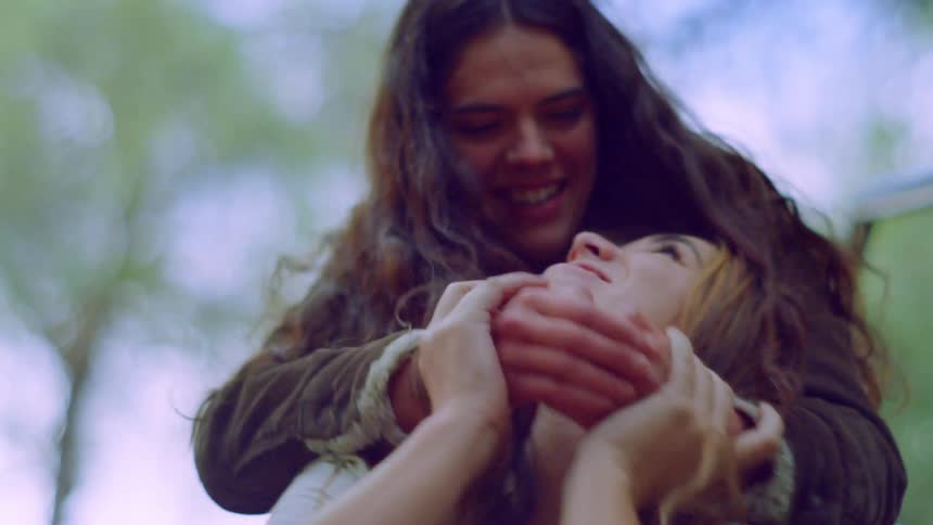 A woman covers the eyes of her friend and gives her a hug