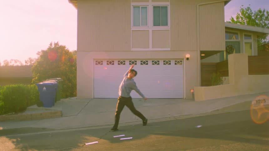 Young man dancing in the street in front of a house in the late afternoon