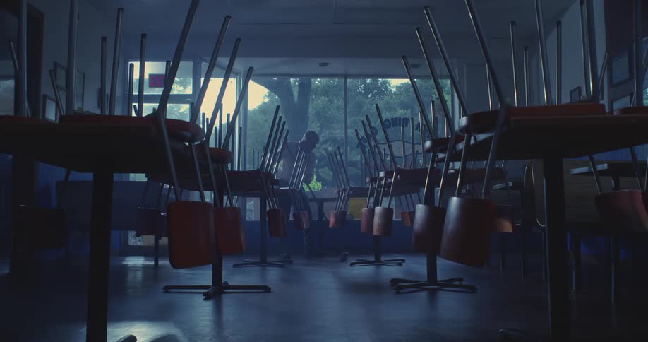 Man in a classroom cleaning with a broom