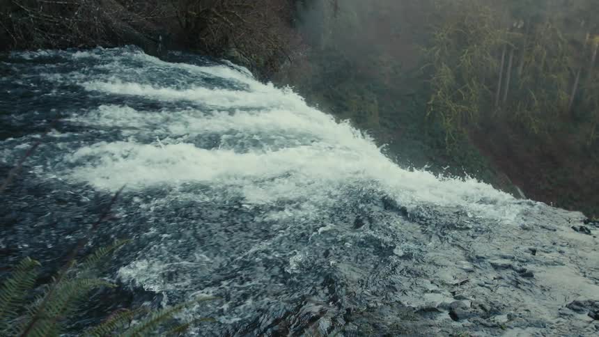 A large waterfall is pouring off the cliff