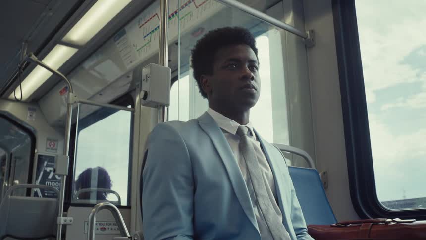 A man in a light blue suit journeys by train