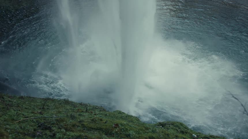 The waterfall pours down into the stream