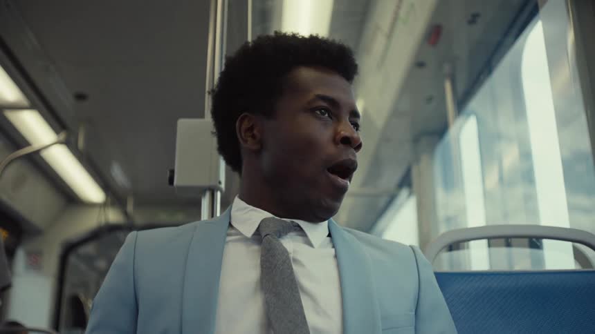 A man yawns as he rides the train