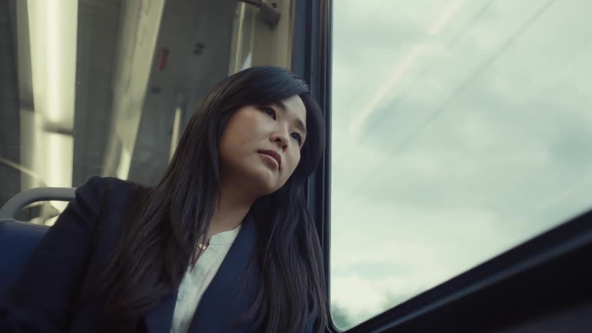 A woman is riding in the train on a cloudy day