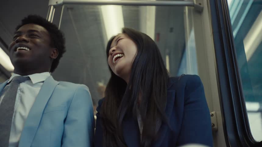Two friends taking public transportation laugh while talking