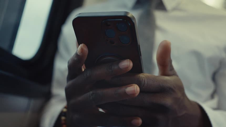 A man sits as he texts on his phone