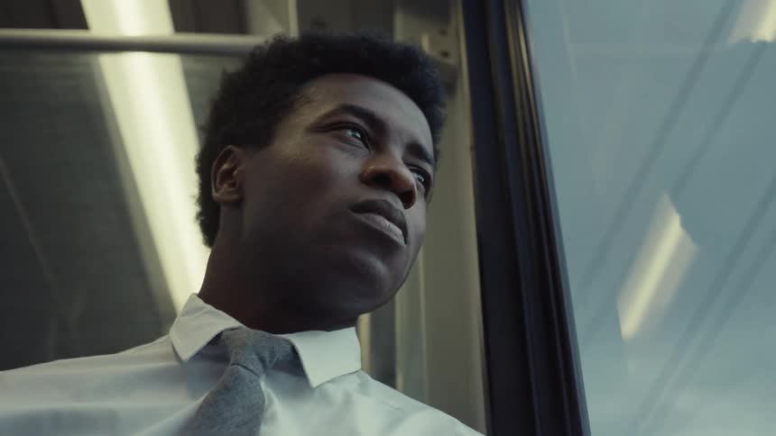Male passenger looks out the window while riding on a bus that passes under an overpass