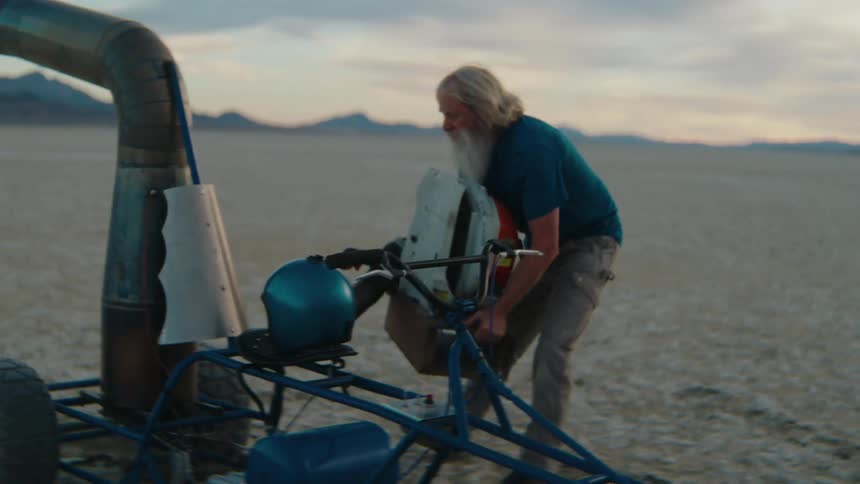 A man carries gear to a motorized buggy in the desert
