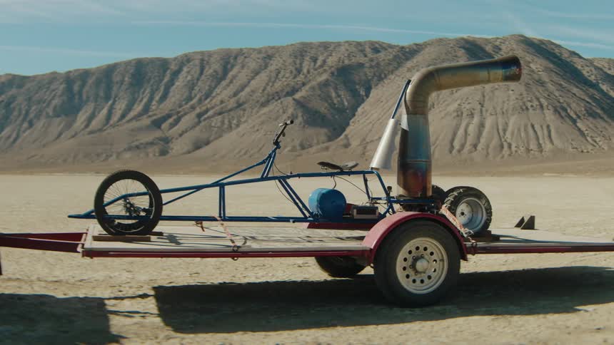 Thrust powered cart sits on a trailer in the desert near hills on a sunny day
